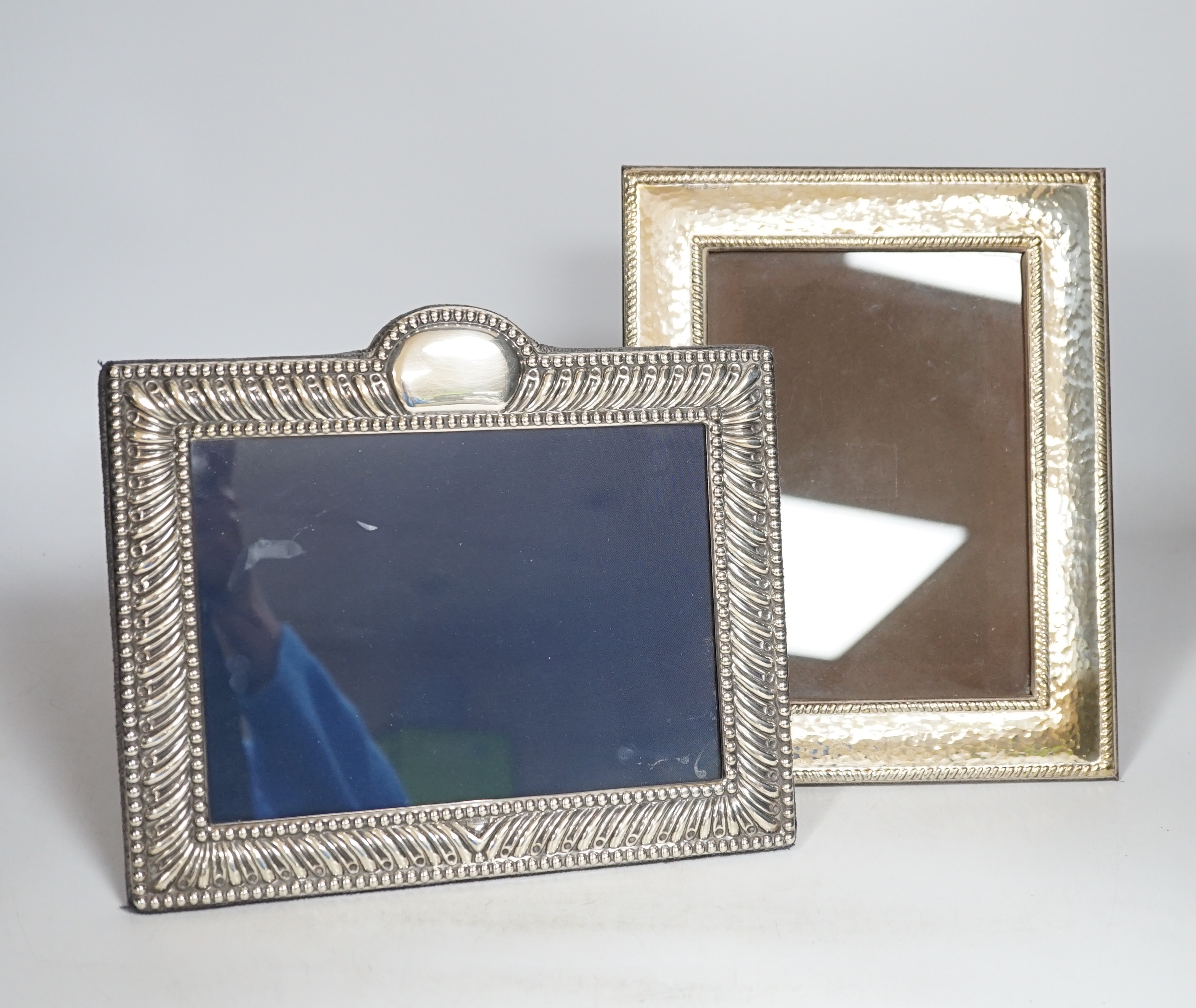 A modern white metal photograph frame with gadrooned border, height 20cm, and a similar planished frame, 24cm
